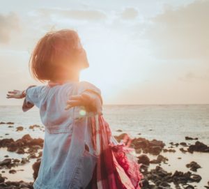 woman at sunrise with her arms spread